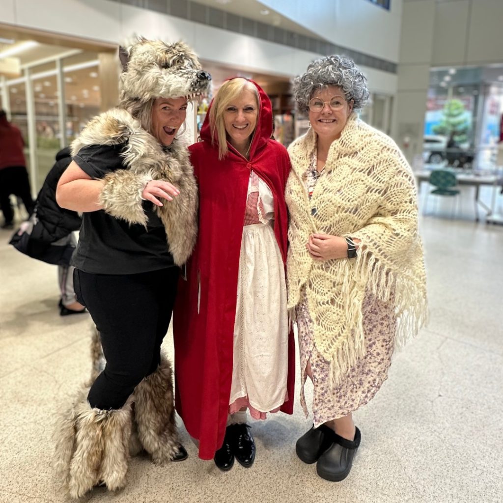 Three women dressed as the fairy tale characters Little Red Riding Hood, wolf and grandma.