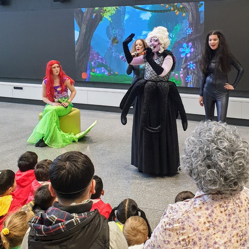 Children watching a singer wearing a black octopus costume perform a song from The Little Mermaid.